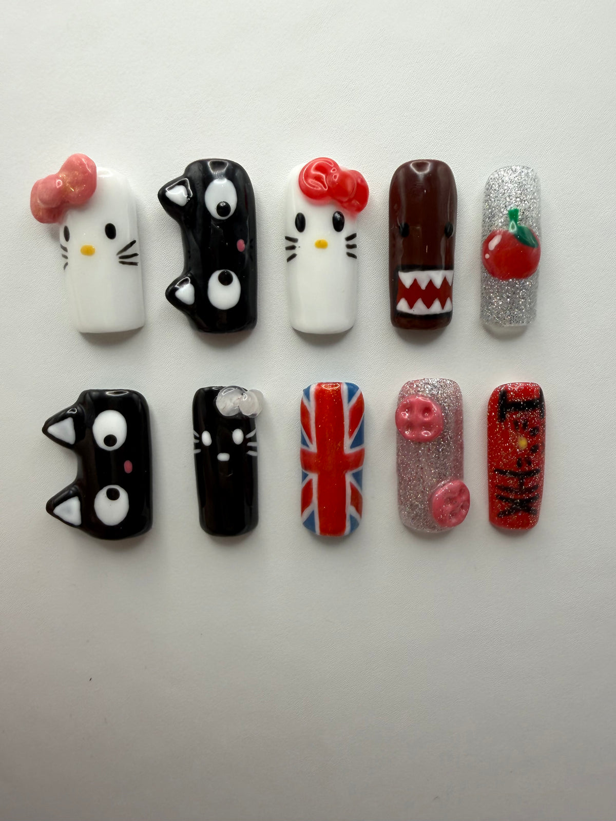 i<3HK press-on nails: ten medium square nails with sculpted bows, black cat faces, a Union Jack, glitter and a cherry charm