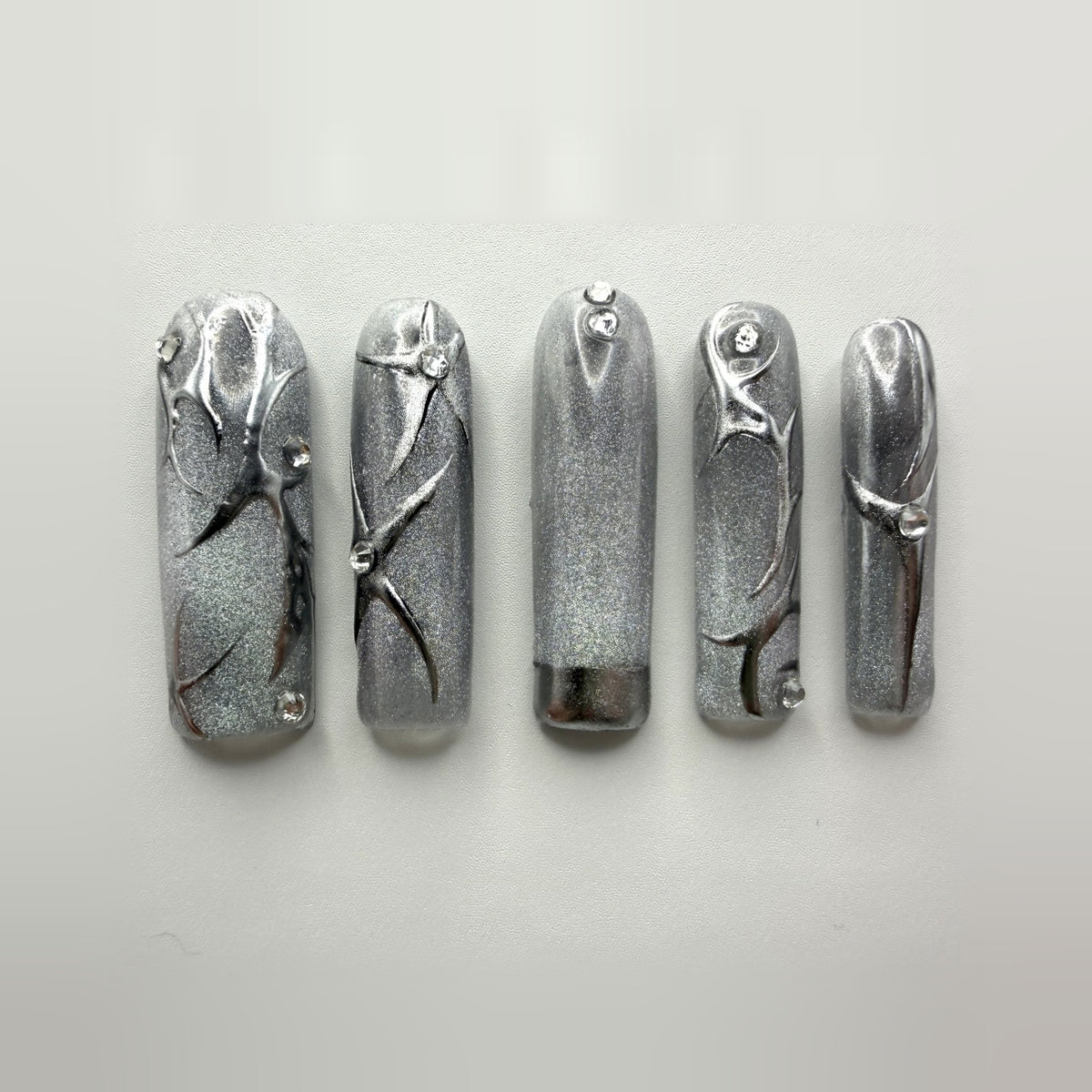 Cyberqueen press-on nails: ten long square silver cat-eye nails with raised mirror-chrome vines and clear rhinestones