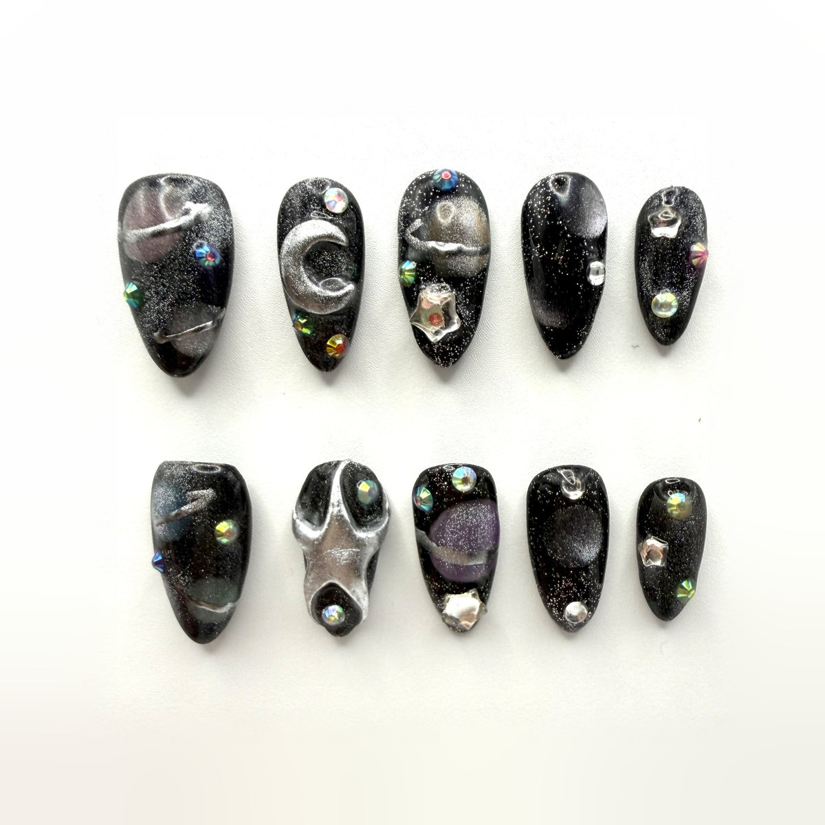 Midnight Oil press-on nails: black glitter almonds with a brushed silver crescent, star studs and iridescent crystals