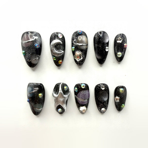 Midnight Oil press-on nails: black glitter almonds with a brushed silver crescent, star studs and iridescent crystals