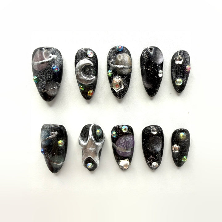 Midnight Oil press-on nails: black glitter almonds with a brushed silver crescent, star studs and iridescent crystals