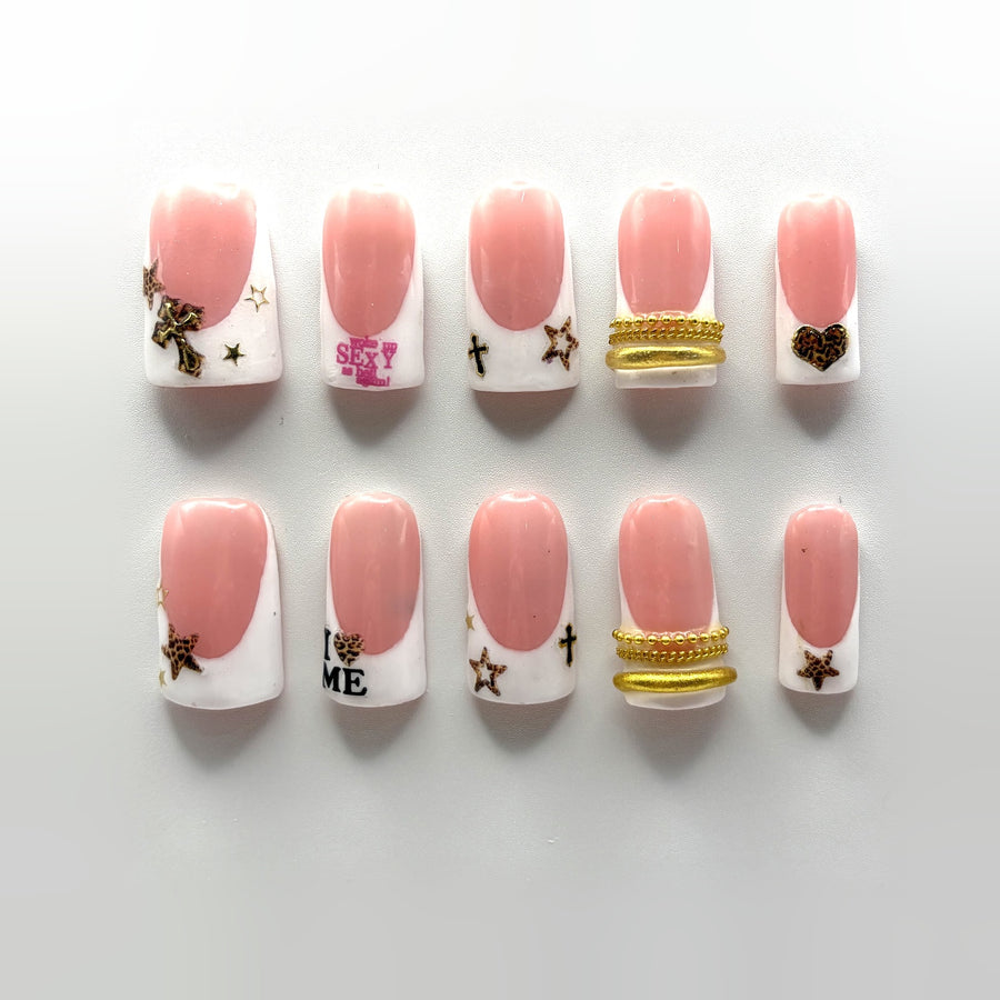 Leopard Saint press-on nails: short square pink French with leopard stars, a gold cross, gold chain cuffs and slogan nails