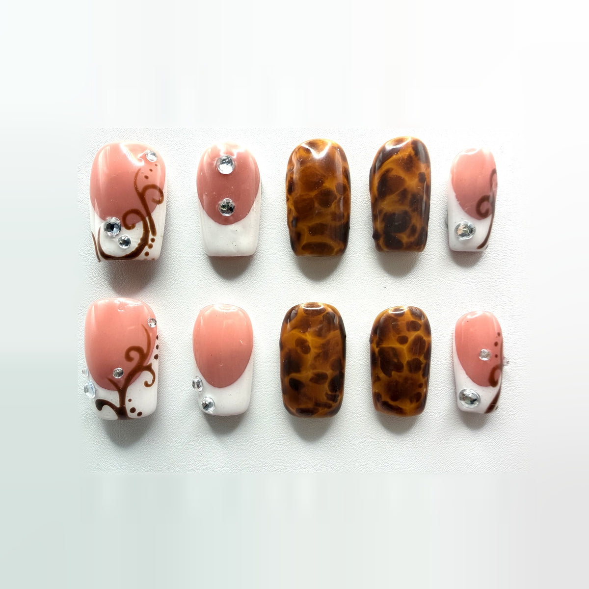 Tuscan French press-on nails: ten short square nails, rosy pink and white French tips with amber tortoiseshell accents, brown vine swirls and rhinestones