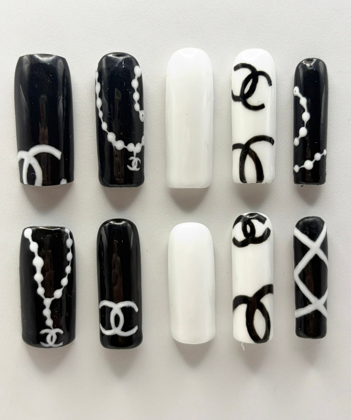 Double C press-on nails: ten long square black and white nails with painted pearl necklaces and double-C line work